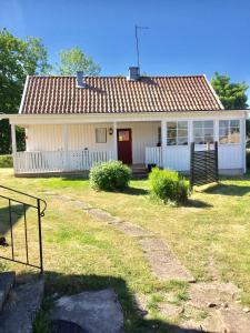ein kleines weißes Haus mit rotem Dach in der Unterkunft Farbror Alfreds Stuga Sjöutsikt in Köpingsvik