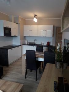 - une cuisine avec des placards blancs, une table et des chaises dans l'établissement Apartament Aga, à Szklarska Poręba