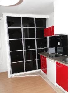 a kitchen with red cabinets and a large window at Appartement TROCADERO in Paris