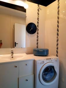 a bathroom with a washing machine and a clock on the wall at Appartement typique Rouen centre tout confort in Rouen