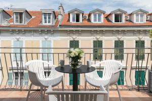 a table and chairs on a balcony with a building at Hotel Florence Nice in Nice