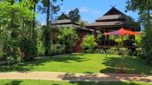 a house with an umbrella in front of a yard at Nan Seasons Boutique Resort in Nan