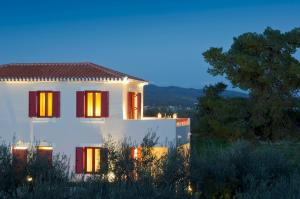 a white house with red shuttered windows at night at Makis Inn Resort in Thermisia