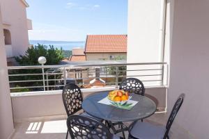 una mesa con sillas y un bol de fruta en el balcón en Apartments Dora en Makarska
