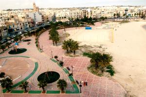 a view of a beach with palm trees and a city at Water's Edge Hotel in Birżebbuġa