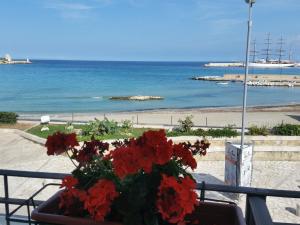 un vaso di fiori rossi seduto su un tavolo vicino alla spiaggia di Hotel Profumo Di Mare a Otranto
