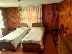 zwei Betten in einem Zimmer mit Holzwänden in der Unterkunft Guesthouse am Museum in Mestia