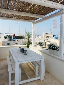 a white table and bench on a balcony with a view at Dimora Madina by MANZONI COLLECTION in Monopoli