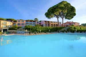 uma grande piscina em frente a alguns edifícios em Hôtel Les Jardins De Sainte-Maxime em Sainte-Maxime