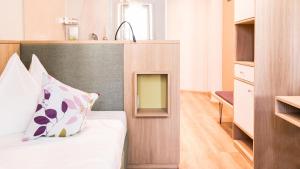 een slaapkamer met een bed en een hoofdeinde met een kussen bij Flora Hotel & Suites in Merano