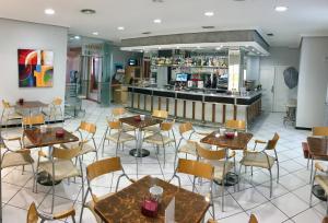 a restaurant with tables and chairs and a bar at Hotel El Emigrante in Villanueva de la Serena
