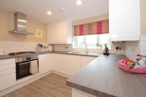 ヨークにあるLucy's Lodge- Most Stylish Apartment On Vibrant Bishy Road with Free Parkingの白いキャビネットとコンロ付きオーブンを備えたキッチン