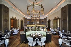 a restaurant with a chandelier and tables and chairs at The Langham London in London