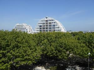 dos edificios blancos detrás de los árboles delante de los árboles en Vittoria Immobilier 10 -Vue Dégagée - Terrasse - chèques vacances acceptés, en La Grande-Motte