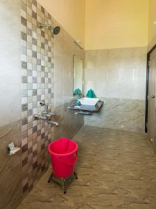 ein Badezimmer mit einem Waschbecken und einem roten Eimer in der Unterkunft Shri Laxmi Narayan Bungalow in Mahabaleshwar