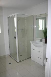 Un baño blanco con ducha y lavabo. en Alexandra Apartments, en Bundaberg 11 fotos más