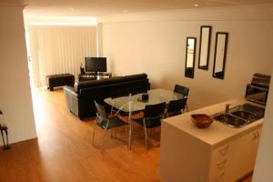 Alexandra Apartments في بوندابرج: غرفة معيشة مع أريكة وطاولة وكراسي