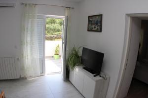 a living room with a tv on a white wall at Apartmani Ivanković in Vrisnik