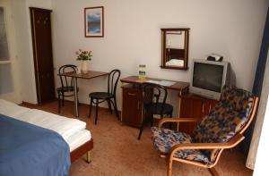 a bedroom with a bed and a desk and a tv at Siesta Club Hotel in Harkány