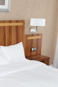 a bed with a wooden headboard and a table with a lamp at Hotel The Originals du Grand Monarque Nantes Gare in Nantes