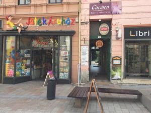 ulica ze sklepami i ławką przed budynkiem w obiekcie Rozmaring Apartman Pécs w mieście Pecz