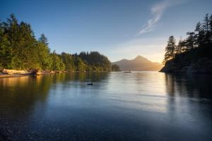 a lake with trees and a mountain in the background at Porteau Cove Olympic Legacy Cabins in Furry Creek