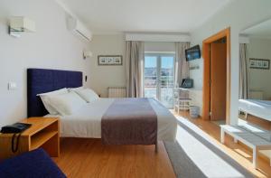 a hotel room with a bed and a balcony at Hotel D. Dinis in Leiria