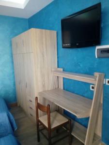 Habitación con escritorio y TV en una pared azul. en B&B DA DILETTA, en Rieti
