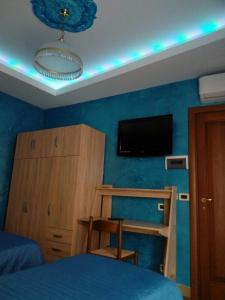 1 dormitorio con pared azul y TV de pantalla plana en B&B DA DILETTA, en Rieti