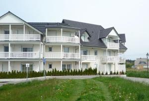 a large white apartment building with a black roof at Wohnen am Yachthafen in Ostseebad Karlshagen