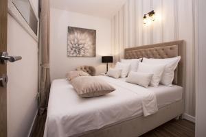 una camera da letto con letto, lenzuola e cuscini bianchi di Apartment Toni Relax a Spalato (Split)