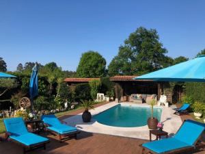 a swimming pool with blue chairs and a blue umbrella at Lugar Meluerda in Meluerda