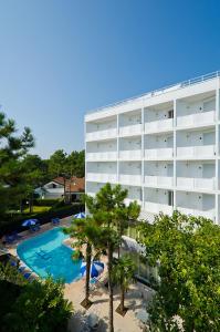 a hotel with a swimming pool next to a building at Hotel Carlton in Lignano Sabbiadoro