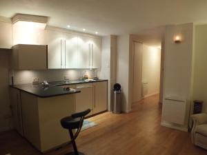 cocina con armarios blancos y encimera negra en Rotherhithe apartment near park and river en Londres