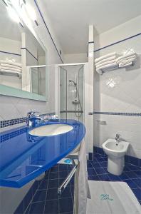 a bathroom with a blue sink and a toilet at Hotel Carlton in Lignano Sabbiadoro
