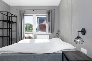 1 dormitorio con cama blanca y ventana en Pensjonat Kocius, en Rewal