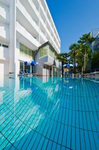 uma piscina com cadeiras e guarda-sóis em frente a um edifício em Hotel Carlton em Lignano Sabbiadoro