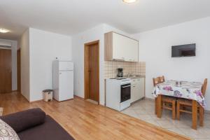 een keuken met witte apparatuur en een tafel in een kamer bij Apartments Mršić in Biograd na Moru