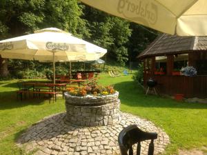 eine Terrasse mit einem Sonnenschirm, einem Tisch und einer Bank in der Unterkunft Gospoda w Starym Młynie in Jugowice + 13 Fotos