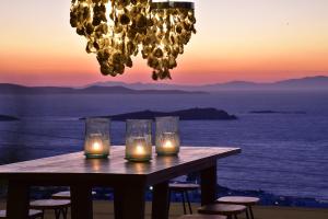 a table with candles on it with a view of the ocean at Hermes Mykonos Hotel in Mikonos
