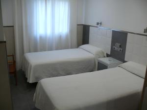 a hotel room with two beds and a window at Hostal la Hispanidad in Málaga