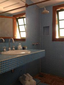 ブジオスにあるPousada Kailaniの青いタイル張りのバスルーム(シンク、鏡付)