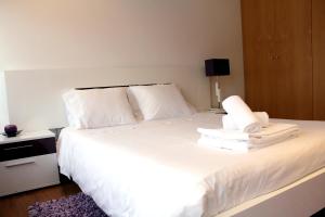 1 dormitorio con 1 cama blanca con sábanas y almohadas blancas en Feel Coimbra Apartments, en Coímbra