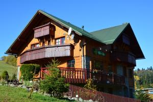 ein großes Holzhaus mit einem Zaun davor in der Unterkunft Penzión Dinda in Stará L'ubovňa