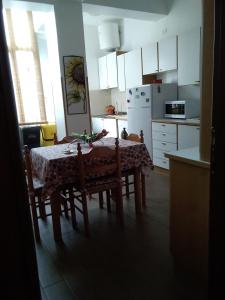 una cocina con mesa y sillas y una cocina con armarios blancos. en B&B "Al Calopinace" en Reggio Calabria