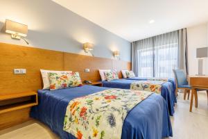 um quarto de hotel com duas camas e uma mesa em Hotel Santo António de Pádua em Fátima