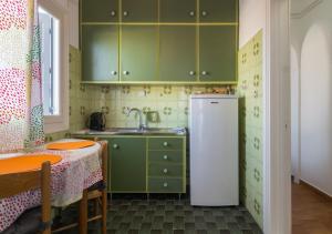 a kitchen with green cabinets and a white refrigerator at Uncle's Titikas Adamas in Adamas