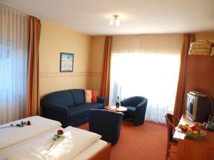 um quarto de hotel com um sofá e uma televisão em Altes Doktorhaus - Hotel Garni em Willingen