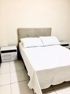 a bedroom with a white bed and a night stand at Morada Center in Uruguaiana