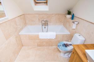 a bathroom with a tub and a toilet at The Garden Studios in Budleigh Salterton